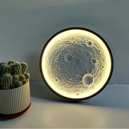 Moon-phase night light on a table with a cactus plant in the background