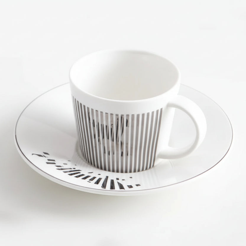 White ceramic cup and saucer with black pattern on a white background